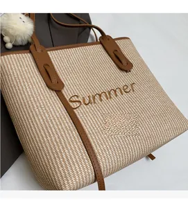Nahaufnahme der gewebten Strohtasche mit Summer-Stickerei und braunen Lederriemen