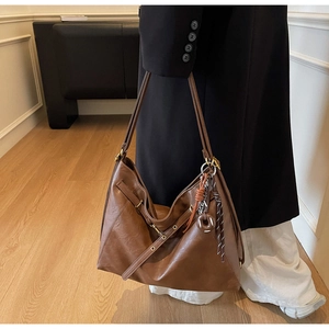 Detailed view of brown leather tote bag with vintage texture and decorative keychain