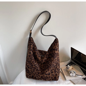 Détail d'un sac seau léopard avec bandoulière en cuir noir et boucle en métal doré