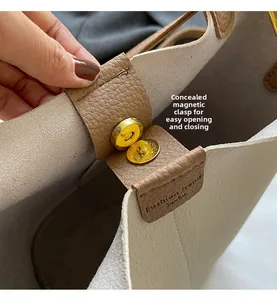 Close-up of beige lychee grain leather bucket bag with hidden magnetic gold buckle
