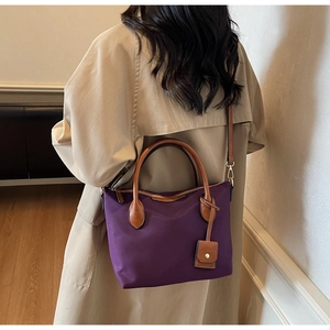Detail der violetten Nylon-Tasche mit Ledergriffen und Schultergurt getragen von einem Model