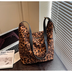 Détail d'un sac hobo à motif léopard avec bandoulière en cuir noir dans un bureau moderne