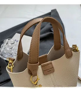 Close-up of contrast leather tote with sturdy handle and gold hardware on blazer background
