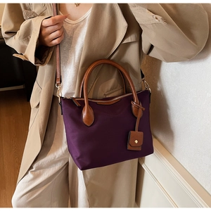 Detailansicht der lila Nylontasche mit braunen Ledergriffen und Reißverschluss-Details