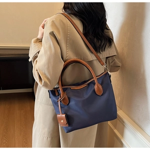Dunkelblaue Nylon-Beuteltasche mit Ledergriffen und goldenen Beschlägen im schicken Interieur