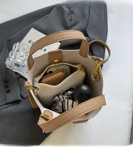 Top view showing spacious interior of beige bucket bag with daily items like phone and umbrella