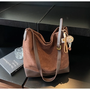 Macro view of dark brown suede tote bag with leather straps and golden buckle detail