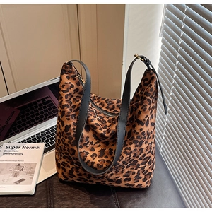 Gros plan d'un sac cabas léopard avec bandoulière en cuir noir et fermeture éclair