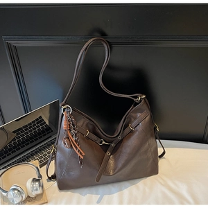 Brown faux leather hobo bag for commuting with laptop and office props on white desk