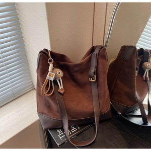 Detail of vintage brown suede tote bag with leather strap and plush charm accent
