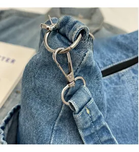 Détail de la boucle métallique argentée et de l'anneau en D sur le sac en jean bleu