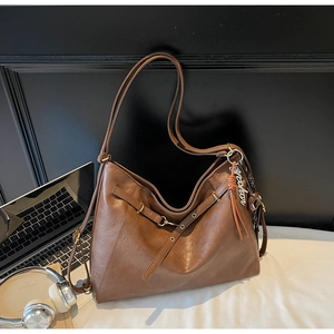 Detailed view of brown large tote bag featuring metal charm and faux leather texture