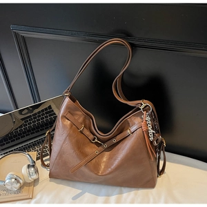 Detail of vintage brown PU leather tote bag with a metallic Sepaton pendant for daily commute