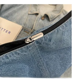 Vue macro du tissu denim bleu clair avec fermeture éclair noire et curseur en métal argenté