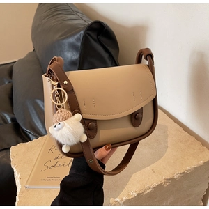 Detail of vintage saddle bag with plush lamb pendant and leather strap texture