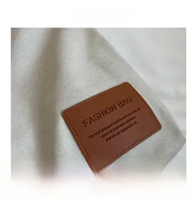 Detail of fashion bag logo on canvas texture with brown leather embossed label