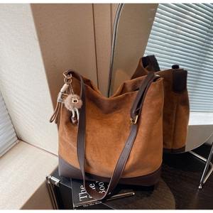 Detail of suede and leather patchwork bucket bag with cute plush bear charm