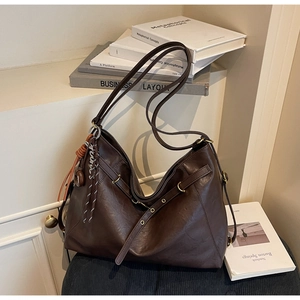 Close-up of deep brown hobo tote bag featuring woven rope charm and gold hardware
