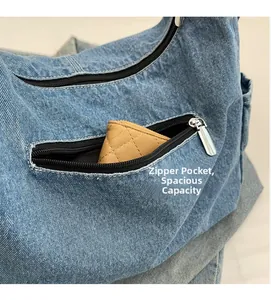 Gros plan sur la poche zippée avant d'un sac bandoulière en denim montrant la capacité