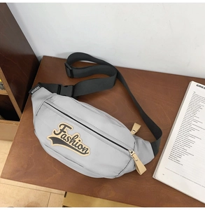 Gros plan sur le sac bandoulière en nylon gris clair avec broderie et sangle noire