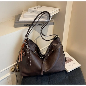 Detail of dark brown hobo bag featuring vintage textured leather and a braided tassel charm