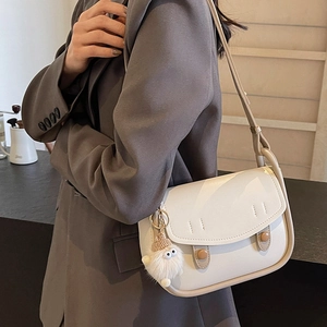 Minimalist cream shoulder bag with plush pendant on dark blazer for 2024 fashion