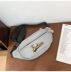 Vue détaillée du sac bandoulière en nylon gris montrant l'écusson brodé Fashion logo