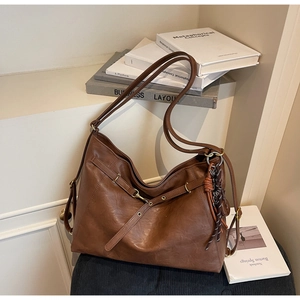 Detailed macro view of dark brown vintage faux leather texture and metallic buckle on tote