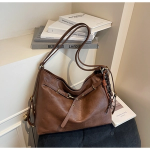 Close-up of vintage brown tote bag with matte leather texture and tassel detail