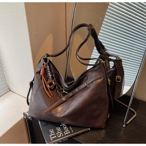 Detail shot of the vintage coffee PU leather texture and decorative strap on the tote bag