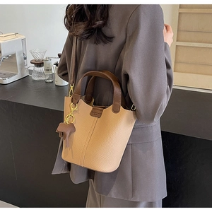Detail of a khaki leather bucket bag with an elephant charm and detachable shoulder strap