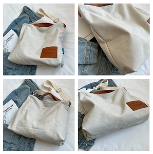 Detail view of the cream canvas tote bag with brown leather patch and woven straps