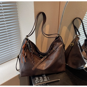 Detailed side view of dark brown faux leather tote with woven knot and letter pendant