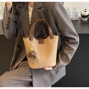 Detail of khaki bucket bag with brown handles and a cute elephant leather pendant