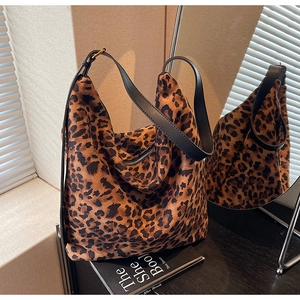 Détail d'un sac cabas imprimé léopard avec bandoulière en cuir noir et fermeture éclair argentée