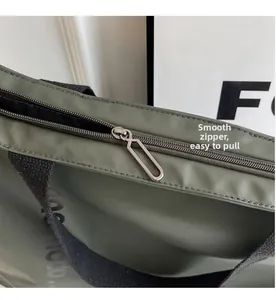 Close-up of smooth metal zipper and durable nylon fabric on dark green tote bag