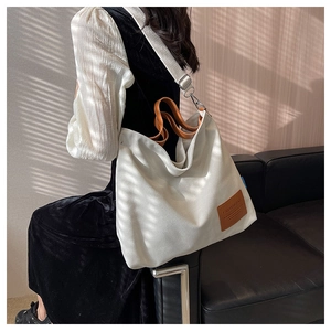 Detail of white canvas tote bag with brown leather straps and adjustable shoulder strap