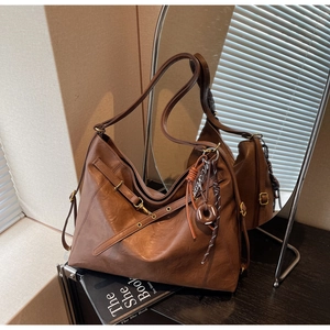Detailed view of brown tote bag with vintage texture, brass buckle, and donut charm