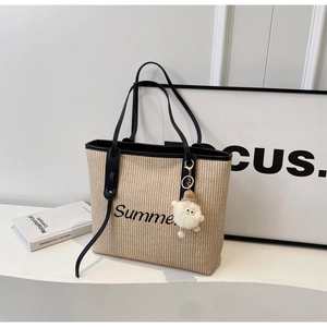 Detail der gewebten Strohtasche mit schwarzem Summer-Aufdruck und Plüsch-Augenanhänger