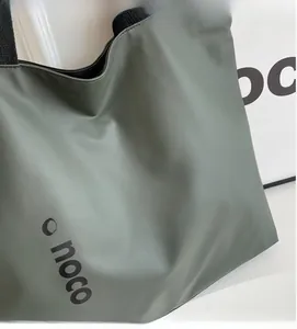 Detail shot of grey-green tote bag showing soft matte leather texture and one noco logo