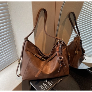 Close-up of vintage brown leather tote bag with donut pendant and adjustable strap