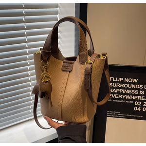 Detail of lychee pattern leather bucket bag with contrasting colors and elephant charm