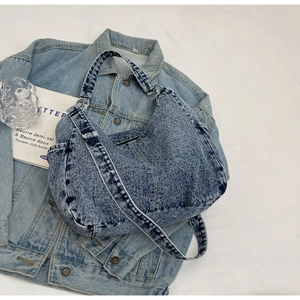 Sac fourre-tout en denim lavé avec large bandoulière posé à plat sur fond blanc