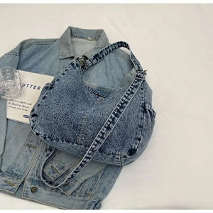 Gros plan sur un sac à bandoulière en denim vintage avec poches latérales et large sangle