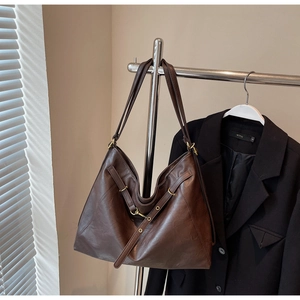 Detail view of the brown leather tote bag with an adjustable strap and metal buckle