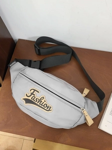 Sac de poitrine en nylon gris clair avec inscription sur fond de bois sombre