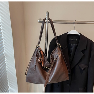 Detailed view of dark brown faux leather tote with textured finish and woven pendant