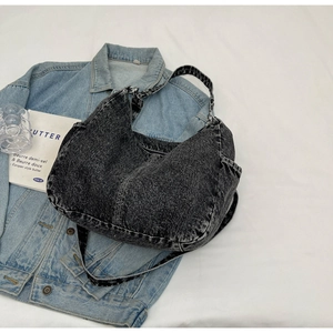 Gros plan du sac Hobo en denim noir délavé avec poche latérale et large bandoulière denim