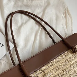 Close-up of woven straw tote bag featuring smooth brown leather straps and V-shaped texture