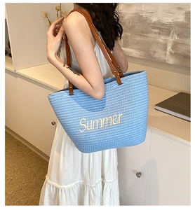 Detail of light blue straw tote with Summer embroidery and brown leather straps